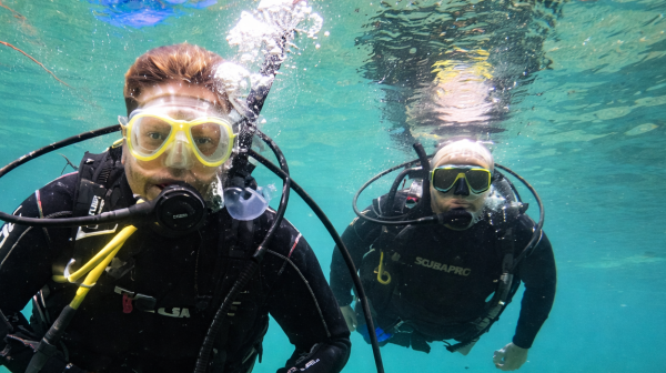 Two scuba divers underwater with clear blue water background.