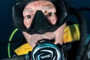 Scuba diver underwater in mask and regulator, close-up view.
