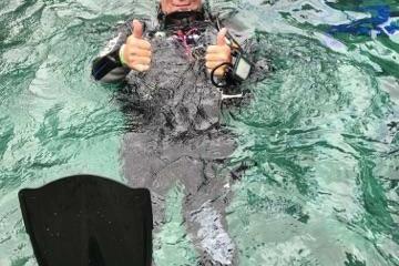 Scuba diver giving thumbs up while floating in water.
