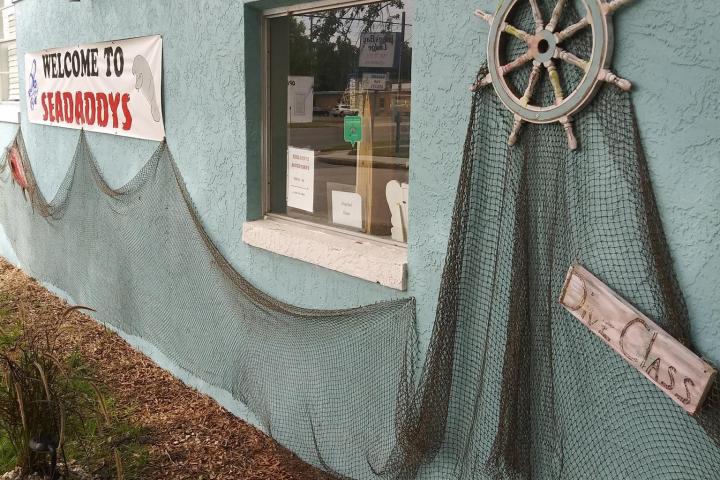 Turquoise wall with fishing nets, ship's wheel, and 'Welcome to Seadaddys' sign.