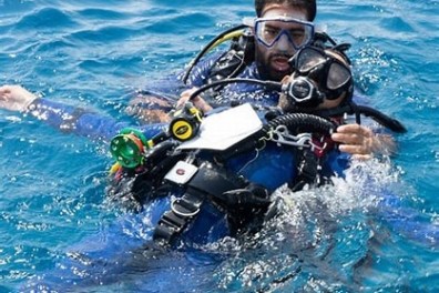 Two divers in scuba gear perform a rescue practice in the open sea.