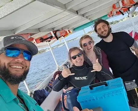 Four people smiling on a boat with life jackets hanging overhead.
